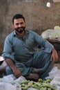Vertical shot of a Pakistani male with a beard in a market selling fruits in a shalwar kameez
