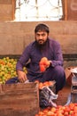 Vertical shot of a Pakistani male with a beard selling fruits in a purple shalwar kameez