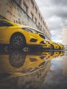 Vertical shot of parked yellow cars reflecting on a puddle