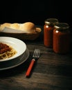 Vertical shot of pasta in a bowl on the table with bread and two jars of sauce Royalty Free Stock Photo