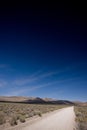 Vertical shot of a path at Death Valley Desert with mountains and cloudscape in the background