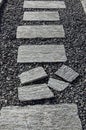 Vertical shot of a pathway with stone decks on top of small stones Royalty Free Stock Photo