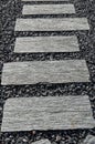 Vertical shot of a pathway with stone decks on top of small stones Royalty Free Stock Photo