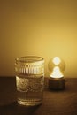 Vertical shot of a patterned glass next to a lamp, artsy aesthetic