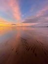 Vertical shot of a peaceful sunset at Morecambe Bay with sand visible in the transparent water