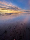 Vertical shot of a peaceful sunset at Morecambe Bay with sand visible in the transparent water