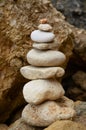 Vertical shot of pebbles behind a cliff balanced perfectly on top of each other Royalty Free Stock Photo