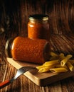 Vertical shot of penne pasta with two jars of sauce on a cutting board on the table under the lights Royalty Free Stock Photo