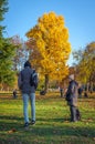 Vertical shot of people in City park under yellow leaves tree in Budapest