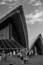 Vertical shot of people standing in front of the Sydney Opera House in Black and White