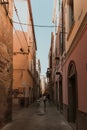 Vertical shot of people walking on the alleyway in the middle of buildings Royalty Free Stock Photo