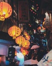 Vertical shot of people walking with umbrellas under the paper lanterns at night time