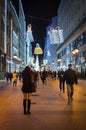 Vertical shot of people walking under Christmas decorations in the street of Budapest at night