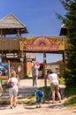 Vertical shot of people at the Western City park entrance with wooden towers and retro entry board.