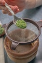 Vertical shot of a person adding green matcha tea powder in a sieve Royalty Free Stock Photo