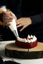 Vertical shot of a person adding white cream on a fancy red velvet cake in a heart shape