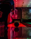 Vertical shot of a person bowling in an arena under bright led lights