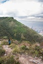 Vertical shot of a person on Colombia mountains path in Bogota with cityscape and cloudy sky