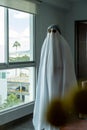 Vertical shot of a person covered by a white sheet,with sunglasses,a hat, in appearance of a ghost