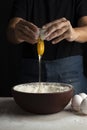 Vertical shot of a person dropping an egg into the bowl with flour