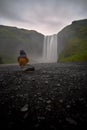 Vertical shot of a person enjoying the beautiful view of Skogafoss waterfall in Iceland