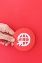 Person holding a small internet globe icon with a cursor isolated on a red background Royalty Free Stock Photo