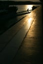 Vertical shot of a person leaving the ship and the sunset reflecting in the sea in the background Royalty Free Stock Photo