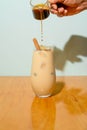 Vertical shot of a person pouring coffee into a glass of iced cappuccino