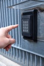 Vertical shot of a person ringing the gate intercom in the daylight