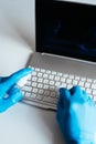 Vertical shot of a person sanitizing a laptop and keyboard