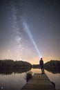 Vertical shot of a person standing on a boardwalk admiring the Milky Way and the starry night