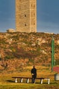 Vertical shot of a person standing in front of the Tower of Hercules in Coruna, Galicia, Spain