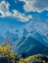Vertical shot of a person standing with the huge Himalayan mountains and the sky in the background.