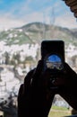 Vertical shot of a person taking a photo of a village with his smartphone