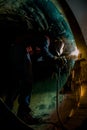 Vertical shot of a person in uniform welding in a dark tunnel