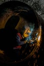 Vertical shot of a person in uniform welding in a dark tunnel