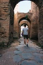 Vertical shot of a person walking in old neighborhoods with triumphal arches during daytime