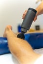 Vertical shot of a Physiotherapist massaging the client& x27;s leg an electric massager