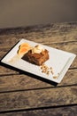 Vertical shot of a piece of cake decorated with walnuts, ice cream, and oranges on a white plate