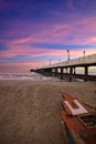 Vertical shot of a pier with stone walls and lampposts at the beach with a purple sky at sunset Royalty Free Stock Photo