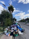 Vertical shot of a pile of rubbish and overflowing trash bins on the side of the road
