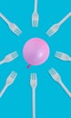 Vertical shot of a pink balloon with disposable plastic forks on a blue background Royalty Free Stock Photo