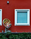 Vertical shot of a pizza satellite dish antenna on a red wall