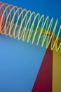 Vertical shot of plastic rainbow magic spring toy against colorful background with copy space Royalty Free Stock Photo