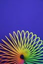 Vertical shot of plastic rainbow magic spring toy isolated on blue background with copy space