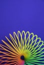 Vertical shot of plastic rainbow magic spring toy isolated on blue background with copy space Royalty Free Stock Photo