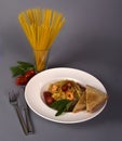 Vertical shot of a plate with cooked pasta with a glass of raw pasta