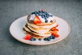 Vertical shot of a plate with gourmet pancakes with cream, strawberries, and blueberries