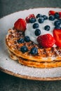 Vertical shot of a plate with gourmet waffles with cream, strawberries, and blueberries Royalty Free Stock Photo