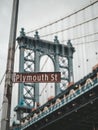 Vertical shot of the Plymouth street sign and the Brooklyn bridge in the background, New York, USA.